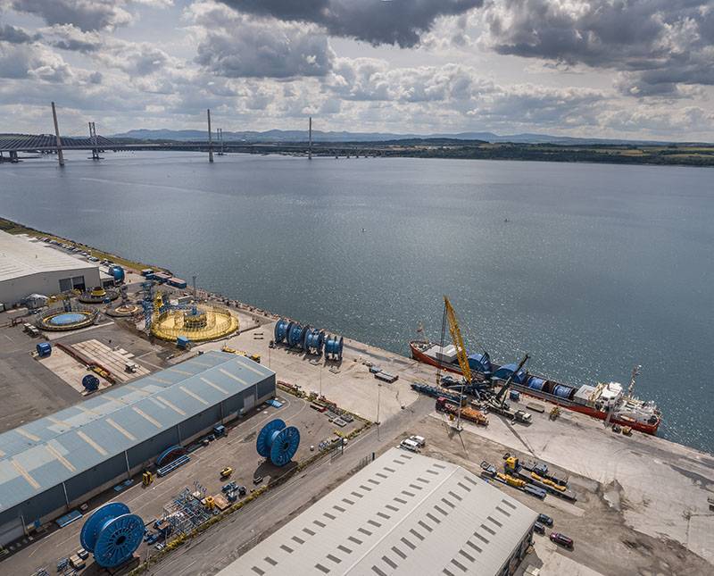 a drone view of a bulk vessel discharging and Oceaneering carousel at North Wall at Forth Ports Rosyth with Queensferry Crossing in the background