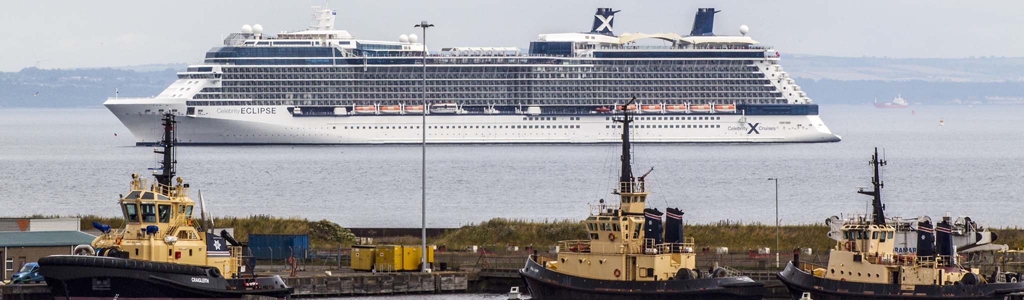 Cruise liner with three tugs in the foreground